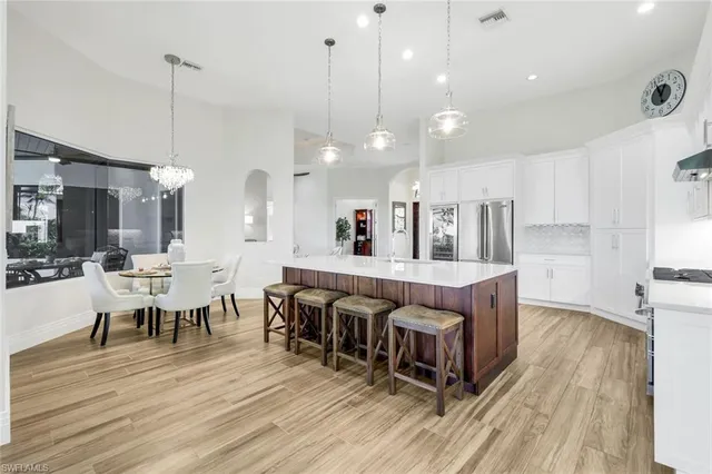 a large room with kitchen island a dining table chairs and a wooden floor