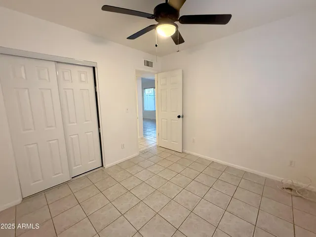 an empty room with closet and a chandelier fan