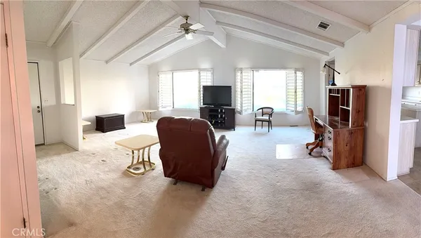 a living room with furniture a flat screen tv and a refrigerator