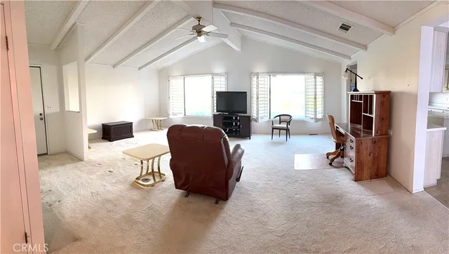 a living room with furniture a flat screen tv and a refrigerator