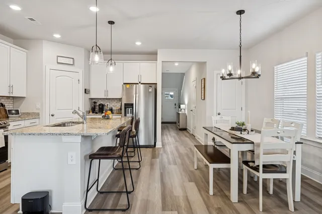 a kitchen with kitchen island a dining table chairs stainless steel appliances and a chandelier