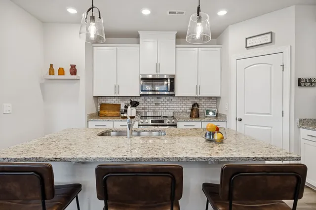 a kitchen with stainless steel appliances granite countertop a sink stove and cabinets