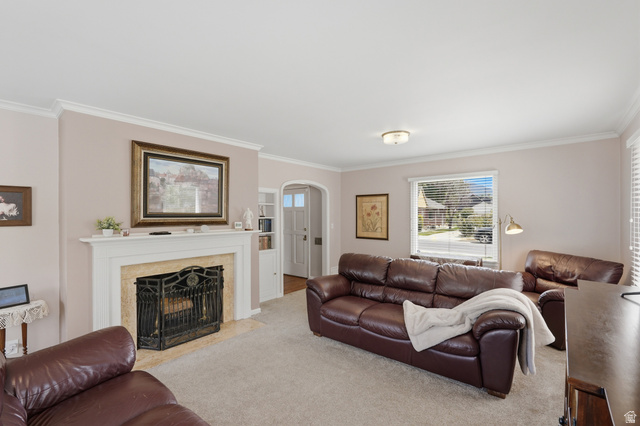7576 South Jefferson Street Midvale, UT 84047 - Photo 6 of 53 Living room featuring a fireplace with a stone surround and white mantel, crown molding, light-colored walls, and a large window with blinds