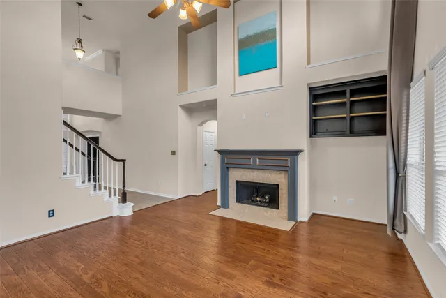 a view of an empty room with wooden floor fireplace and a window