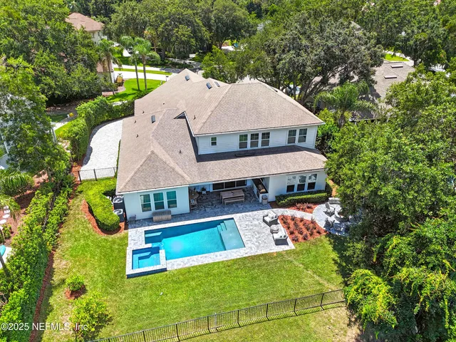 an aerial view of a house with swimming pool and large trees