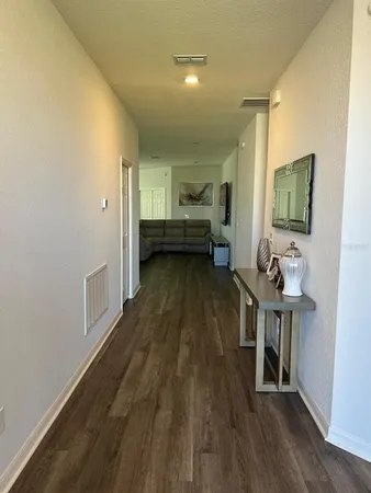 a view of a hallway with wooden floor and furniture