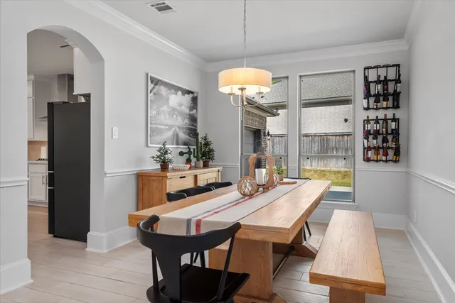 a dining room with wooden floor a chandelier a wooden table and chairs