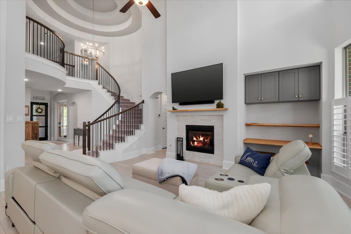 207 Ladner Street Willis, TX 77318 - Photo 4 of 46 This spacious living room features a modern open layout with high ceilings and a grand curved staircase. It includes a cozy fireplace, built-in shelves, and a mounted TV. The room is filled with natural light, creating a warm and inviting atmosphere. Notice the rotunda ceiling over the stairs that Westin is known for.