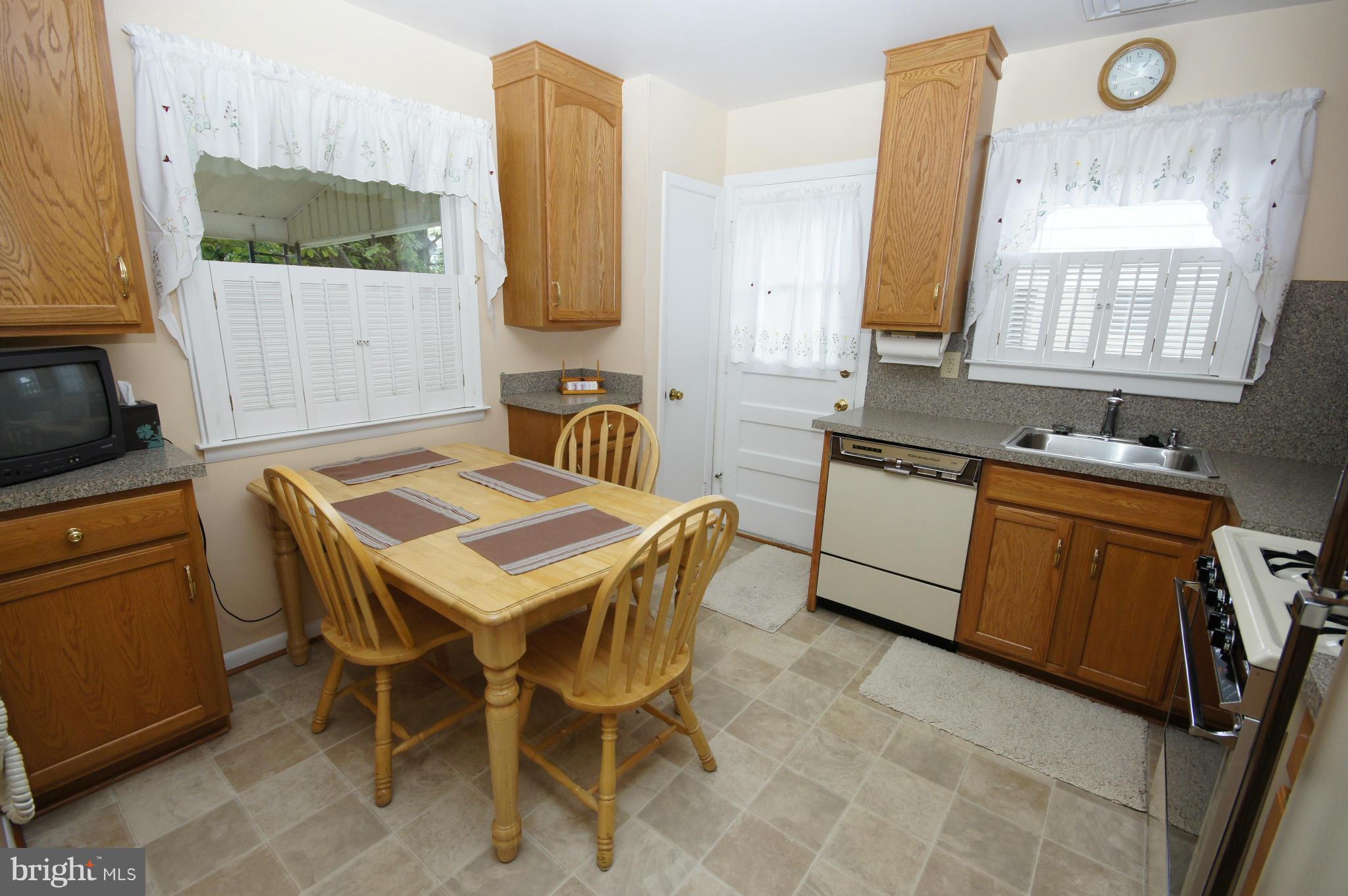 6202 Gilston Park Road Baltimore, MD 21228 - Photo 5 of 21 a white kitchen with a sink a stove a microwave a dining table and chairs