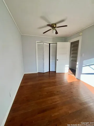 a view of empty room with wooden floor and fan