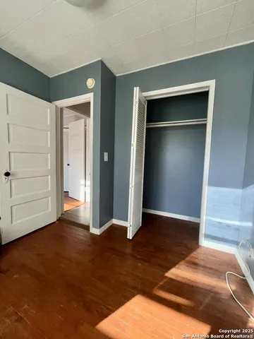 an empty room with wooden floor closet and windows