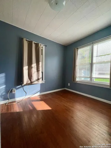 a view of an empty room with window and wooden floor