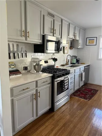 a kitchen with stainless steel appliances granite countertop a stove a sink and white cabinets