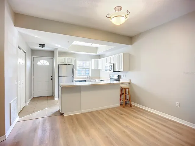 a living room with stainless steel appliances kitchen island granite countertop a sink and cabinets