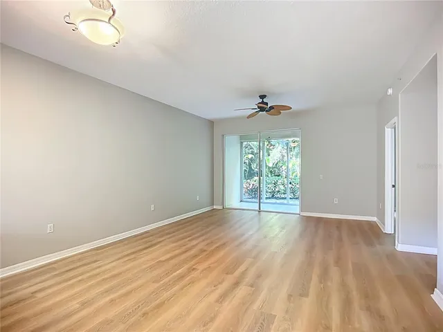 a view of an empty room with kitchen and a window