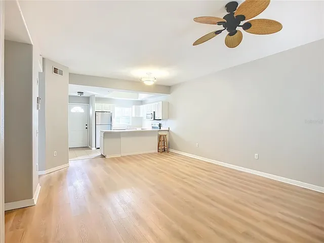 a view of an empty room with a window and wooden floor