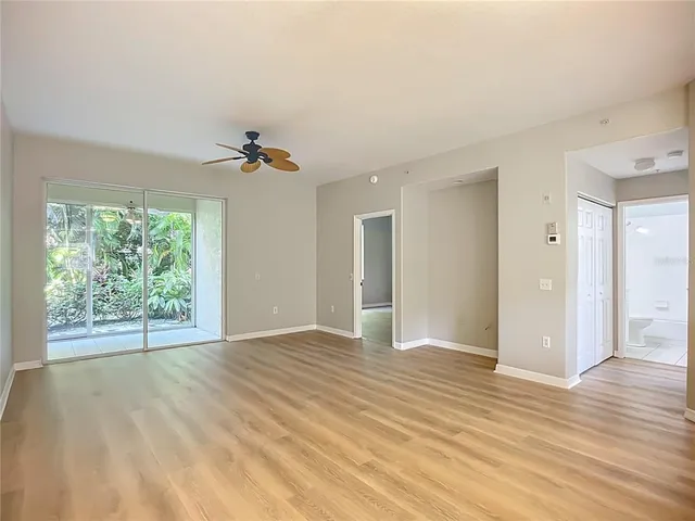 a view of an empty room with wooden floor and a window
