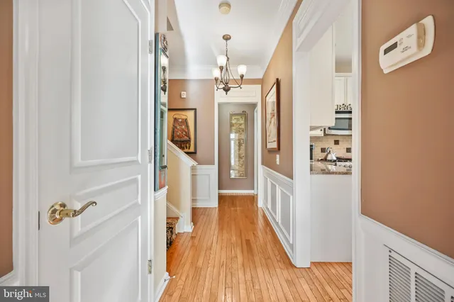 a kitchen with stainless steel appliances granite countertop a stove top oven a sink a refrigerator and white cabinets with wooden floor