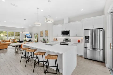 a kitchen with stainless steel appliances a stove a refrigerator a kitchen island a sink and a refrigerator