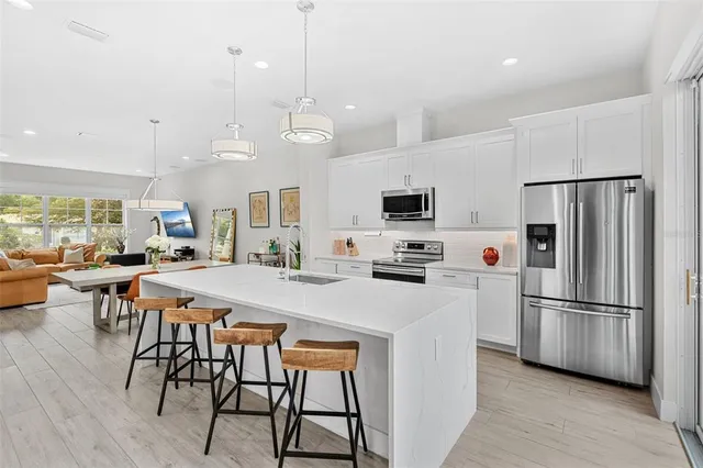 a kitchen with stainless steel appliances a stove a refrigerator a kitchen island a sink and a refrigerator