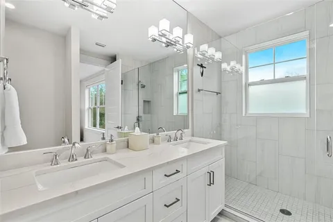 a bathroom with a double vanity sink mirror and shower