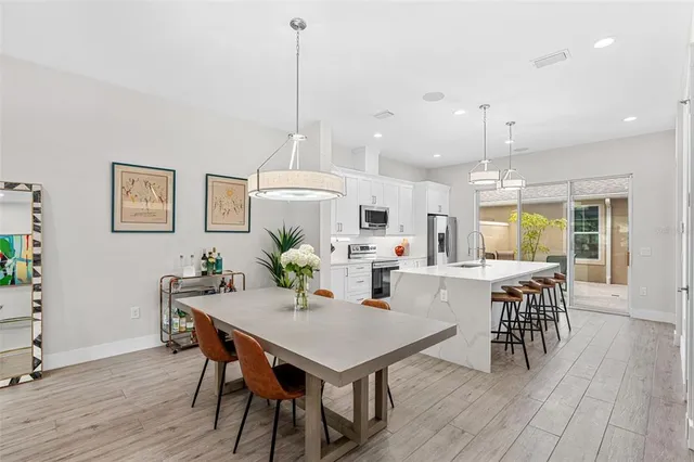 a view of a dining room and livingroom with furniture wooden floor a rug a painting and a chandelier
