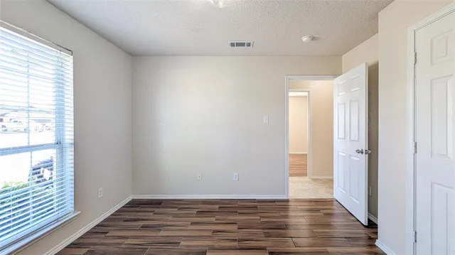 a view of an empty room with wooden floor and a window