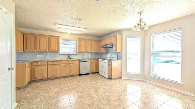 a large kitchen with kitchen island granite countertop a stove a sink dishwasher a dining table and cabinets with wooden floor