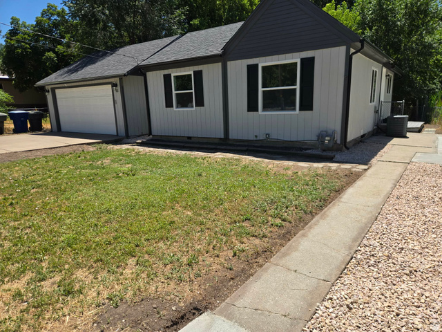 Light gray vertical siding exterior with dark gray trim and white garage door