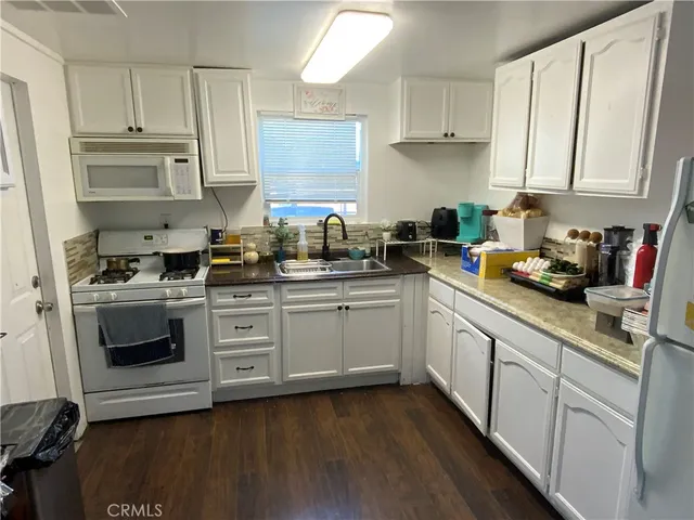 a kitchen with stainless steel appliances white cabinets a sink a stove a refrigerator and white cabinets