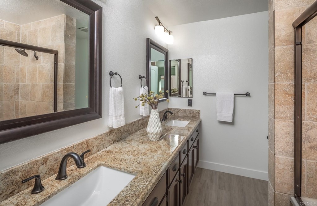 7777 Caminito Monarca, Unit 105 Carlsbad, CA 92009 - Photo 14 of 25 a bathroom with a granite countertop sink a mirror and shower