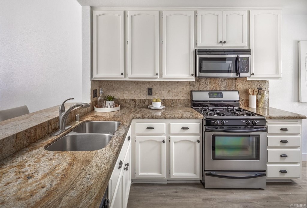 7777 Caminito Monarca, Unit 105 Carlsbad, CA 92009 - Photo 4 of 25 a kitchen with granite countertop a sink stainless steel appliances and cabinets
