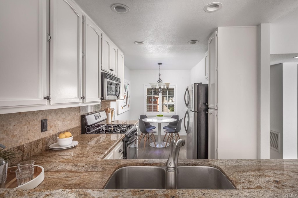 7777 Caminito Monarca, Unit 105 Carlsbad, CA 92009 - Photo 8 of 25 a kitchen with stainless steel appliances granite countertop a sink a stove and a refrigerator