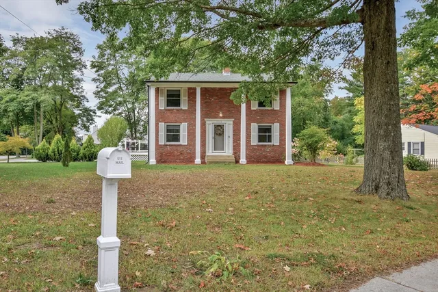 a front view of a house with a yard and tree