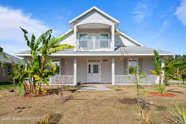 a front view of a house with a yard and potted plants