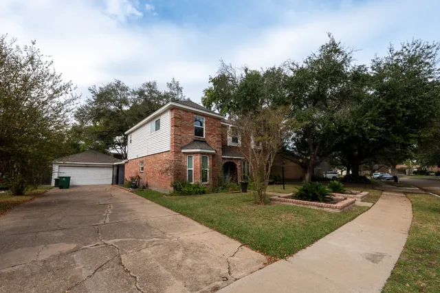 a view of a white house with a big yard plants and large trees