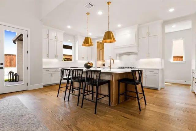 a kitchen with stainless steel appliances granite countertop a table chairs sink and wooden floor