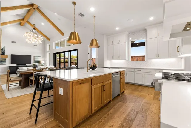 a kitchen with granite countertop a stove a sink a dining table and chairs with wooden floor