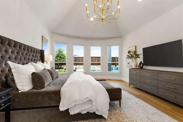 a spacious bedroom with a bed and a flat screen tv