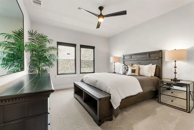a spacious bedroom with a bed a window and potted plant on the dresser