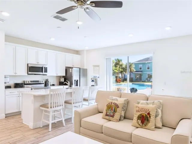 a living room with stainless steel appliances a couch and a view of kitchen