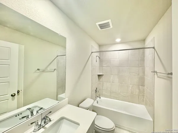 a bathroom with a bathtub shower sink vanity and toilet