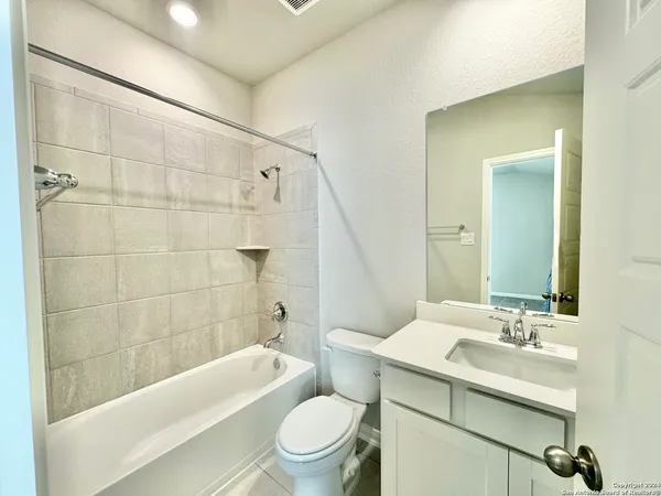 a bathroom with a sink a toilet a mirror a bathtub and shower