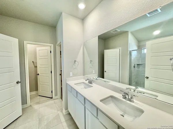 a bathroom with a double vanity sink mirror and shower