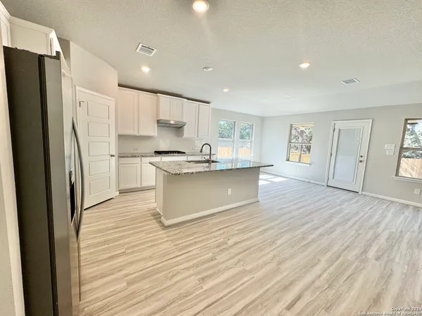 a kitchen with stainless steel appliances granite countertop a refrigerator sink and white cabinets