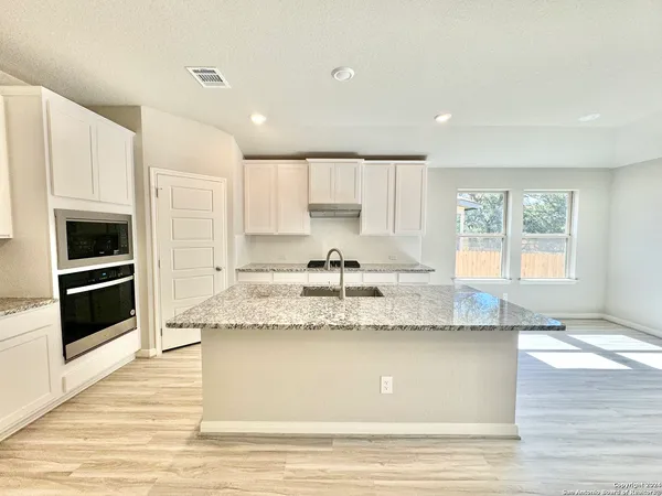 a large kitchen with granite countertop a stove a sink and a granite counter tops