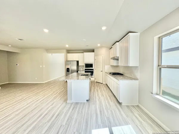a large white kitchen with a white countertops a stove and a wooden floors