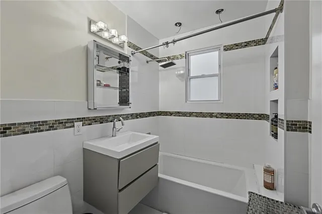 a bathroom with a granite countertop sink mirror vanity and bathtub