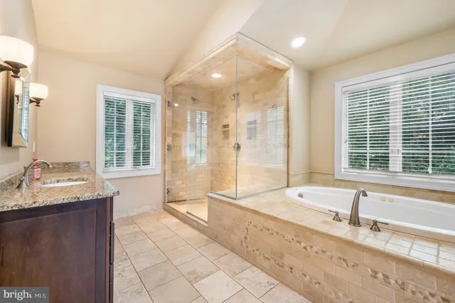 a bathroom with a granite countertop tub sink and mirror