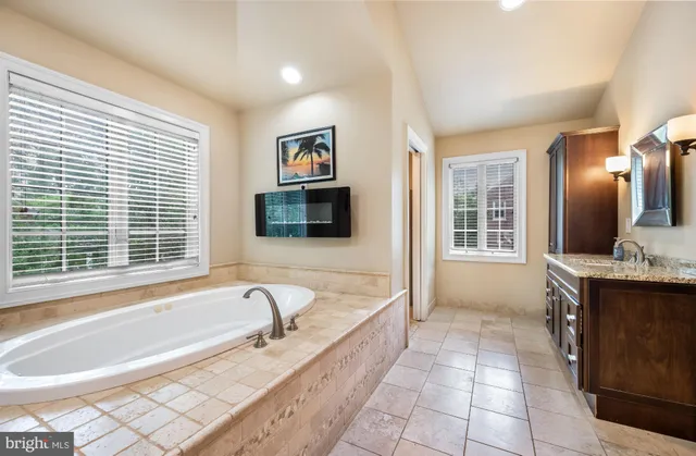 a spacious bathroom with a granite countertop tub sink and mirror